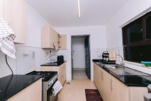 a kitchen with black counter tops and wooden cabinets at Ruaka Radiance 2-Bed Escape in Ruaka