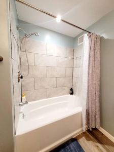 een badkamer met een wit bad en een douche bij First floor Buffalo/Niagara Apt close to stadium in Depew