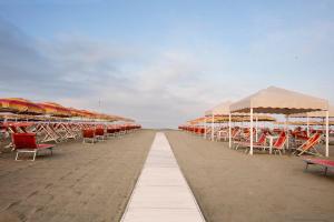 a row of chairs and umbrellas on a beach at Elena House Apartments in Viareggio