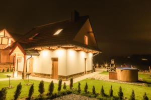 a house with lights on the side of it at night at Chata Stylchyn in Kluszkowce