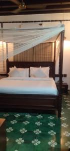 a bedroom with a bed with a canopy and a green carpet at Malabar Kovilakam in Malappuram