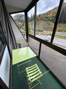 une table verte et une chaise dans une chambre avec fenêtres dans l'établissement Studio situé au pied des pistes de LaBresse, à La Bresse