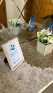 una mesa con un cartel y un jarrón de flores en Monsoon Chalet - شاليه المونسون en Junayz al Janūbī