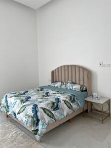 Bett in einem weißen Zimmer mit einem Tisch in der Unterkunft Monsoon Chalet - شاليه المونسون in Junayz al Janūbī