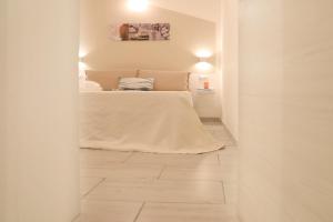 biała sypialnia z łóżkiem i białą podłogą w obiekcie La Corte di Santa Maria w mieście Sassari