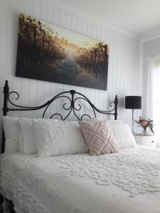 a bedroom with a white bed with a picture on the wall at Vineyard Views Rutherglen in Rutherglen