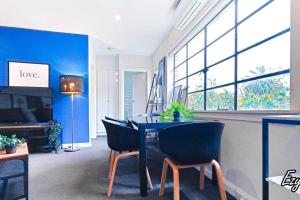 メルボルンにあるMCG 1BR Apartment For Familyの青い壁の客室で、テーブルと椅子が備わります。
