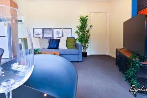 a living room with a blue couch and a glass table at MCG 1BR Apartment For Family in Melbourne