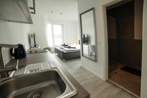 een keuken en een woonkamer met een wastafel en een spiegel bij Livingboxx Karlsruhe in Rheinstetten