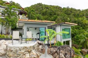 ein Haus auf einem Hügel mit einem Tisch und Stühlen in der Unterkunft The Dreaming View Villa in Haad Yao