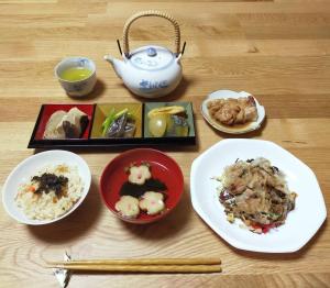 民宿 和合 Minshuku WAGO في تانابا: طاولة مع أطباق من الطعام وقدر الشاي