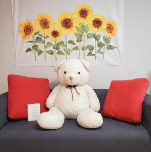 a teddy bear sitting on a couch with two red pillows at Cozy - Warm Studio in Incheon