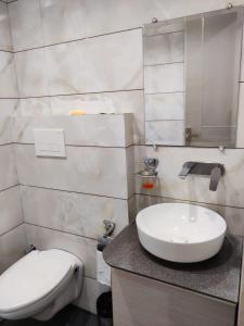 a bathroom with a white sink and a toilet at Hotel Hamilton in Zirakpur