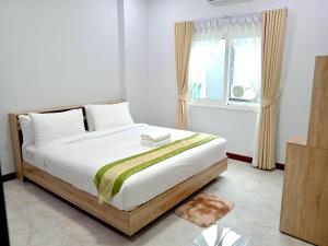 een slaapkamer met een bed met witte lakens en een raam bij Pause Homestay in Ban Khlong Wa