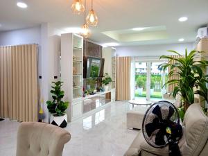 een woonkamer met witte meubels en planten bij Pause Homestay in Ban Khlong Wa