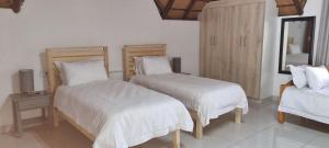 1 dormitorio con 2 camas con sábanas blancas y espejo en LAPA ROOF, en Sandton