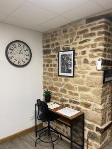 un escritorio contra una pared de piedra con reloj en Les Pichies, T2 Gloria, centre ville, en Digoin