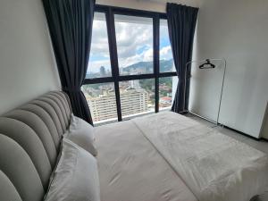 een slaapkamer met een bed voor een groot raam bij Executive Urban Suites - George Town @ Penang in Jelutong