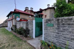 uma casa com uma parede de pedra e uma cerca em Orchard Oasis Home Stay em Mukteshwar