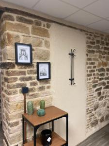 una pared de ladrillo con dos cuadros y una mesa con un cactus en Les Pichies, T2 Gloria, centre ville, en Digoin