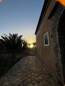 een stenen pad naast een gebouw met de zonsondergang op de achtergrond bij Serdrar Camp in Timganine