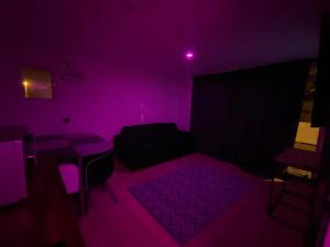 Cette chambre sombre comprend un lit et une lumière violette. dans l'établissement LoVe 1, au Cap d'Agde