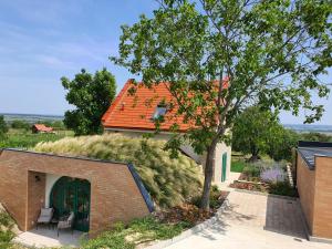 una casa con techo naranja y un árbol en Herczeg-Fekete Cottage Birtokközpont, en Simontornya
