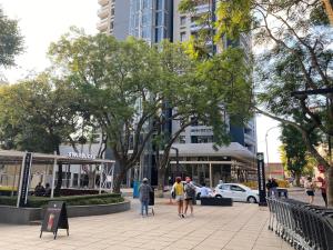 a group of people walking down a sidewalk in a city at The Rosebank Mall Place in Johannesburg