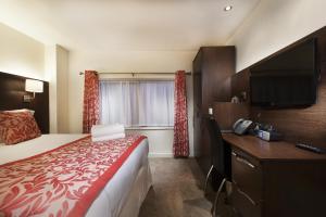 a hotel room with a bed and a desk with a television at Hotel Shepherds Bush London in London