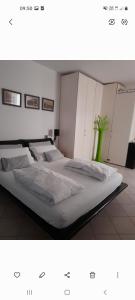 1 Schlafzimmer mit 2 Betten mit weißer Bettwäsche und einer grünen Vase in der Unterkunft Appartamento Merano nel cuore in Meran