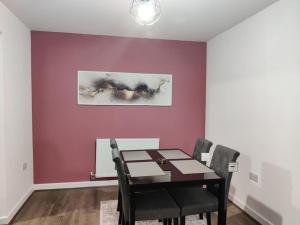 Elegant, Spacious 2bed in Crystal Palace, London في كريستال بالاس: غرفة طعام مع طاولة وجدار أرجواني