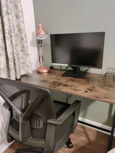 a desk with a computer monitor and a chair at Elegant, Spacious 2bed in Crystal Palace, London in Crystal Palace