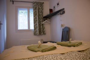 two towels on top of a bed with a window at Bükki csend vendégház in Bükkszentkereszt