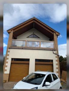 um carro branco estacionado em frente a uma casa em At The Beach em Stevenston