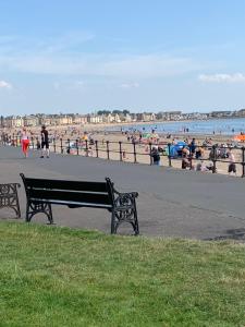 a park bench in front of a beach with people at At The Beach in Stevenston