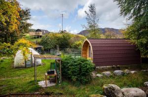 a garden with a small building and a greenhouse at Glentruim Lodge Ecopod in Newtonmore