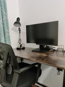 a computer monitor sitting on a wooden desk with a chair at Elegant, Spacious 2bed in Crystal Palace, London in Crystal Palace