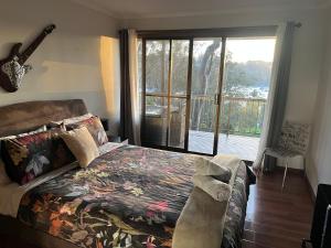 a bedroom with a bed and a large window at Palm beach Sydney, Modern home with water view in Palm Beach