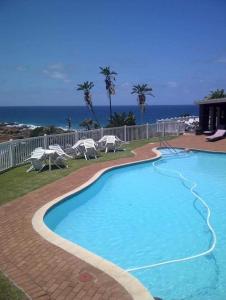 a swimming pool with chairs and the ocean in the background at Villa Del Sol Unit 8 in Margate