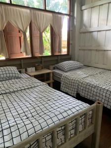 two beds in a room with two windows at Yor Song Hostel Pai in Kampong Huaibū