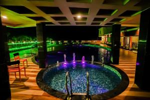 a swimming pool at night with a fountain at Prasant Beach Resort in Mandarmoni