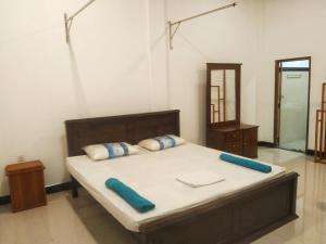 a bedroom with a bed with blue pillows and a mirror at Kalum home in Sigiriya