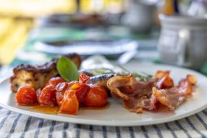 a plate of food with bacon and tomatoes on a table at Seaforth Country House in uMhlali