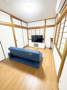 a living room with a blue couch in front of a tv at 無料駐車場有車種制限有!USjまで近く!空庭温泉徒歩圏海遊館!最大7名 in Osaka