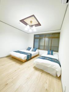 two beds in a room with white walls and wooden floors at 無料駐車場有車種制限有!USjまで近く!空庭温泉徒歩圏海遊館!最大7名 in Osaka