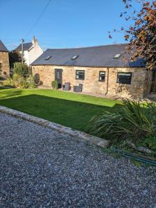 a stone house with a lawn in front of it at The Barn in Shirland