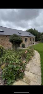 a house with a stone walkway in front of a yard at The Barn in Shirland