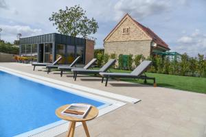 a group of lounge chairs next to a swimming pool at Herczeg-Fekete Cottage Birtokközpont in Simontornya