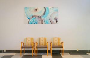 Dos sillas en una habitación con un cuadro en la pared en Royal Inn & Suites, en Akron