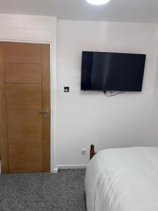 a bedroom with a bed and a flat screen tv on the wall at 7 Venus Road (Room 7) in London